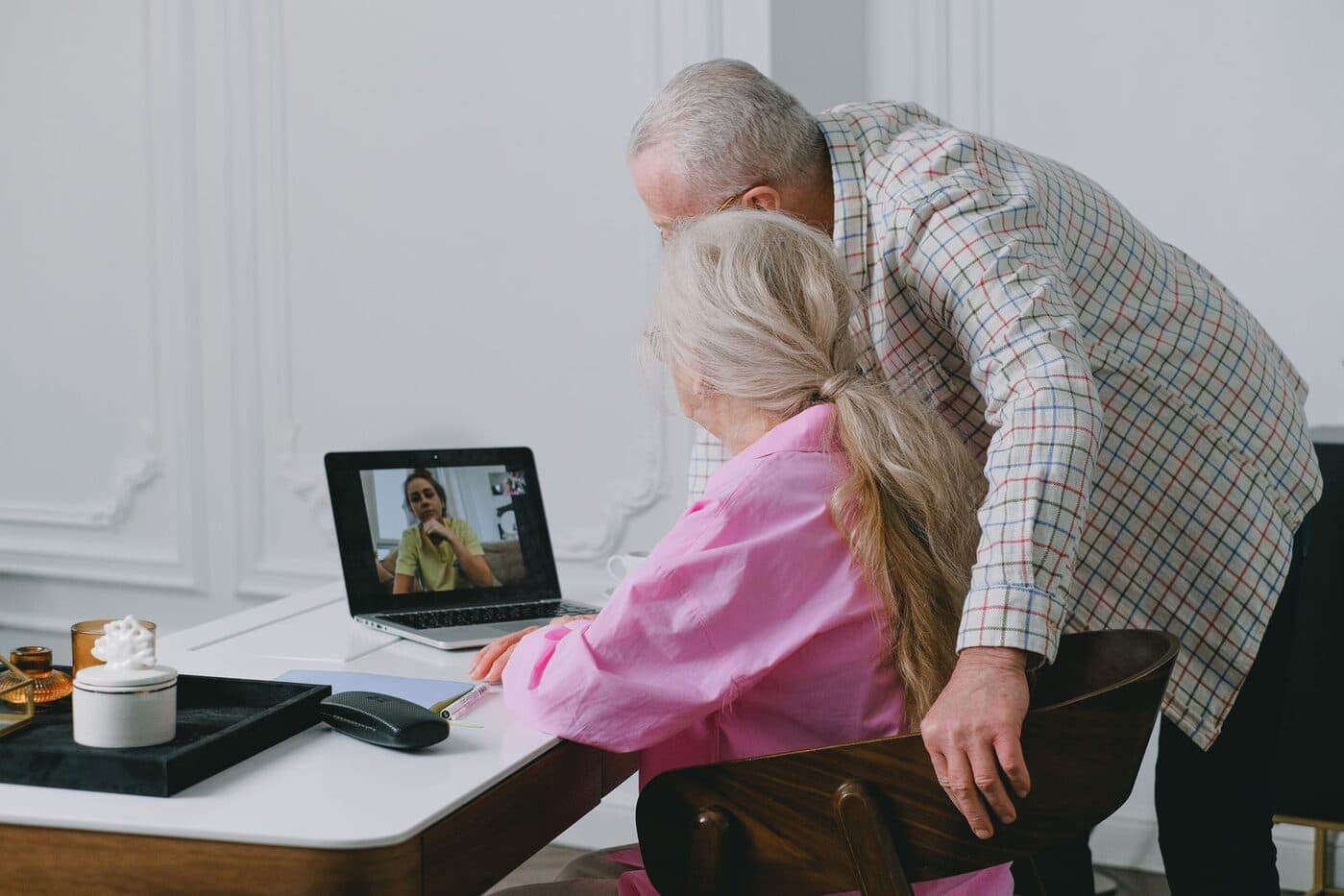 Grandparents watching a wedding livestream together on a laptop